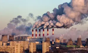Dymiące kominy elektrowni nad miastem, świadczące o złej jakości powietrza.
