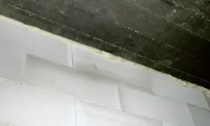Dylatacja komina wykonana pianką montażową między betonowym stropem a białymi bloczkami.