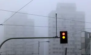 Mgła tak gęsta, że czuć ją w powietrzu. Sygnalizacja świetlna pokazuje czerwone i żółte światło, budynki znikają we mgle.