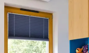 Zasłonięte okno z granatową plisą. Jak zamknąć nawiewnik w oknie? Widoczny mechanizm nad ramą okna.