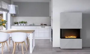 Nowoczesny kominek w kuchni, z płonącym ogniem, stanowi serce tego jasnego, minimalistycznego wnętrza.