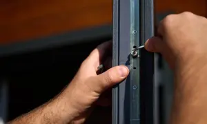 Dłoń z kluczem imbusowym dokonuje regulacji okien Salamander, precyzyjnie dopasowując mechanizm.