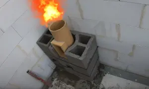 Ogień wydobywa się z ceramicznej rury, która jest częścią mocowania komina systemowego do ściany z pustaków.