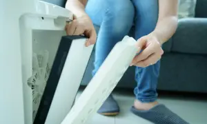 Osoba wyjmuje filtr z oczyszczacza powietrza. Czy filtr HEPA można myć wodą? Zależy od modelu, ten wygląda na jednorazowy.