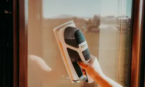 Ręka z odkurzaczem do okien Karcher myje szybę. Idealny moment, kiedy najlepiej myć okna, to słoneczny dzień.