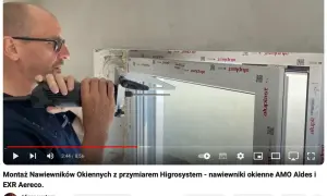 Montaż nawiewnika w oknie. Mężczyzna wierci otwór w ramie okiennej, przygotowując miejsce na nawiewnik.