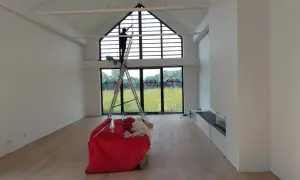 Osoba na drabinie czyści okna, przygotowując wnętrze do sprzątania. Wkrótce będzie można dowiedzieć się, jak usunąć pył po remoncie.