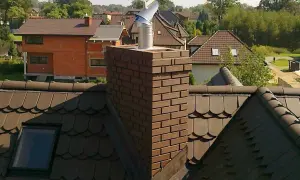 Metalowy daszek na kominie, chroniący przed deszczem. Pokazuje, jak zrobić daszek na komin, by był skuteczny.