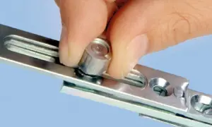 Dłoń reguluje śrubę w mechanizmie okna, zapewniając prawidłową regulację uchyłu okna.
