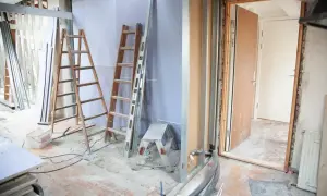 Remont wnętrza z drabinami, materiałami budowlanymi i otwartymi drzwiami. Sprawdzanie dopuszczalnej wilgotności ścian norma.