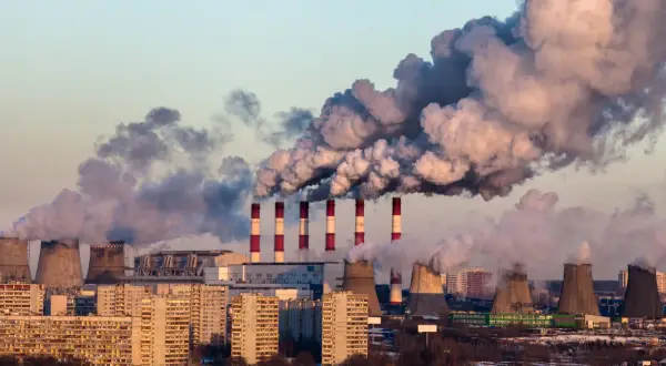 Dymiące kominy elektrowni nad miastem, świadczące o złej jakości powietrza.