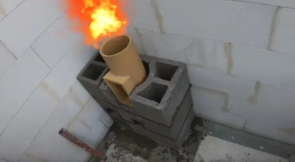Ogień wydobywa się z ceramicznej rury, która jest częścią mocowania komina systemowego do ściany z pustaków.