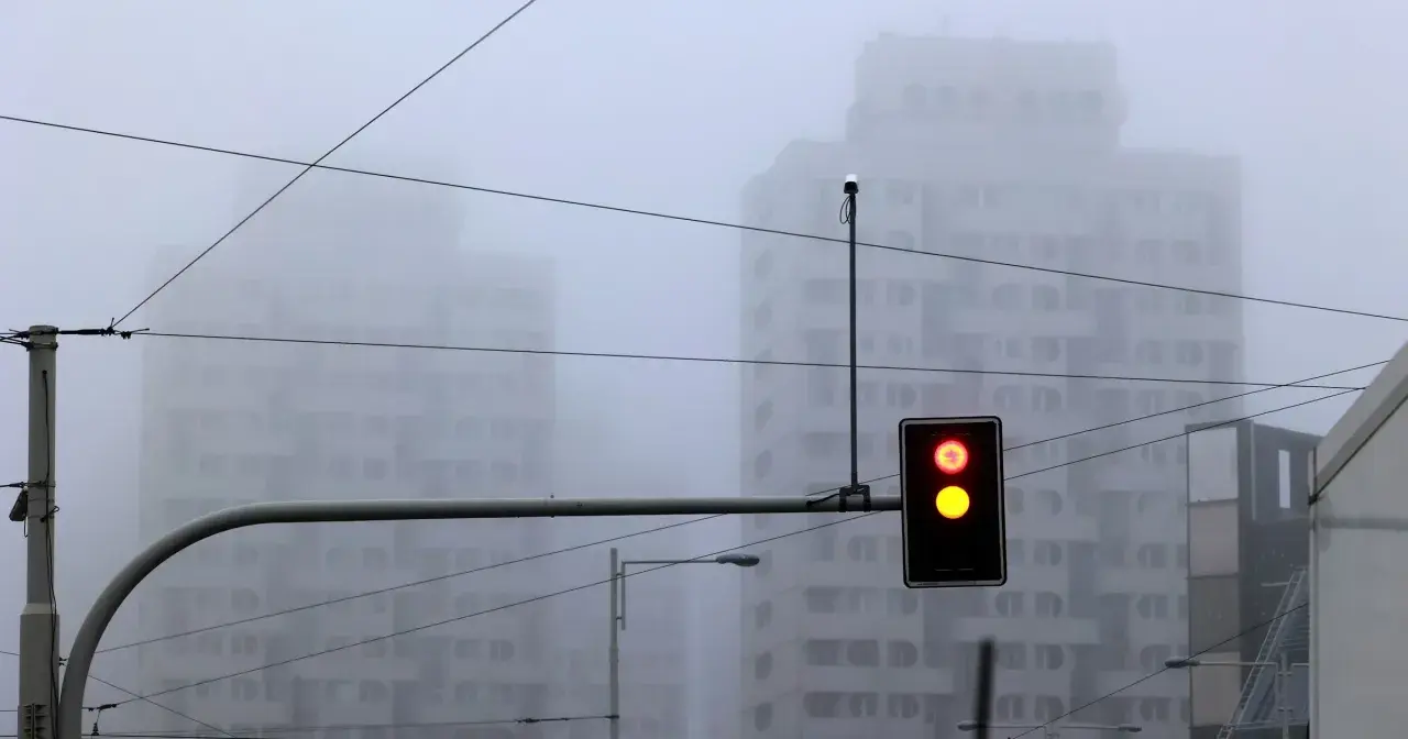 Mgła tak gęsta, że czuć ją w powietrzu. Sygnalizacja świetlna pokazuje czerwone i żółte światło, budynki znikają we mgle.