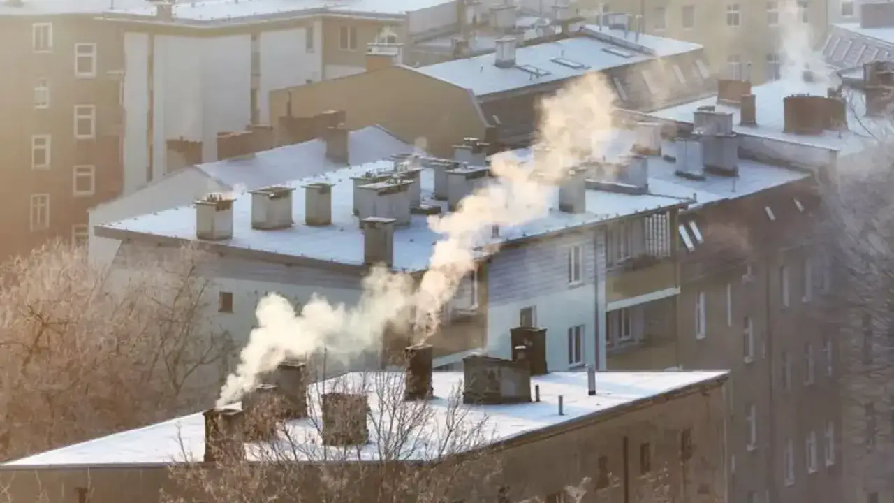 Dym z kominów na tle zaśnieżonych dachów świadczy o zanieczyszczeniu i złej jakości powietrza w mieście.