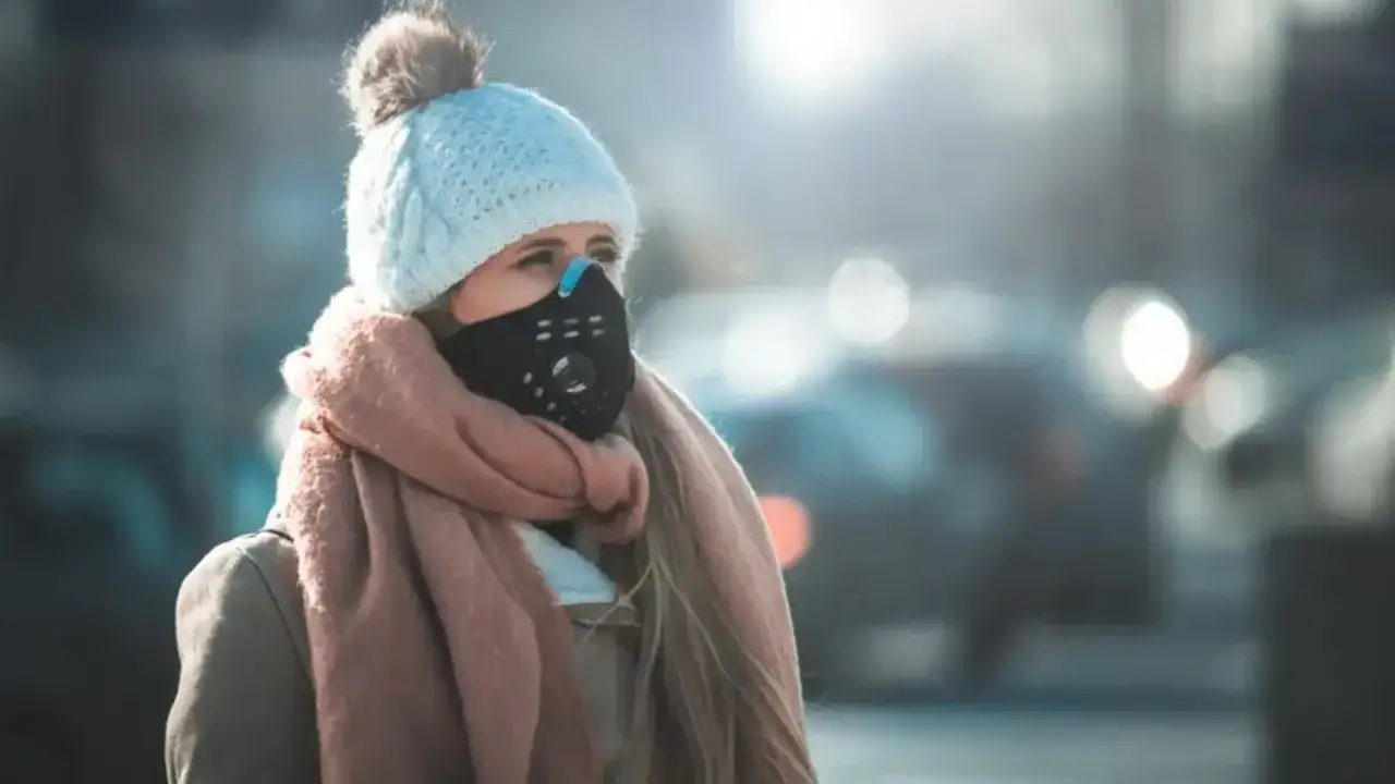 Kobieta w czapce i szaliku nosi maskę ochronną, chroniąc się przed wirusem w powietrzu.