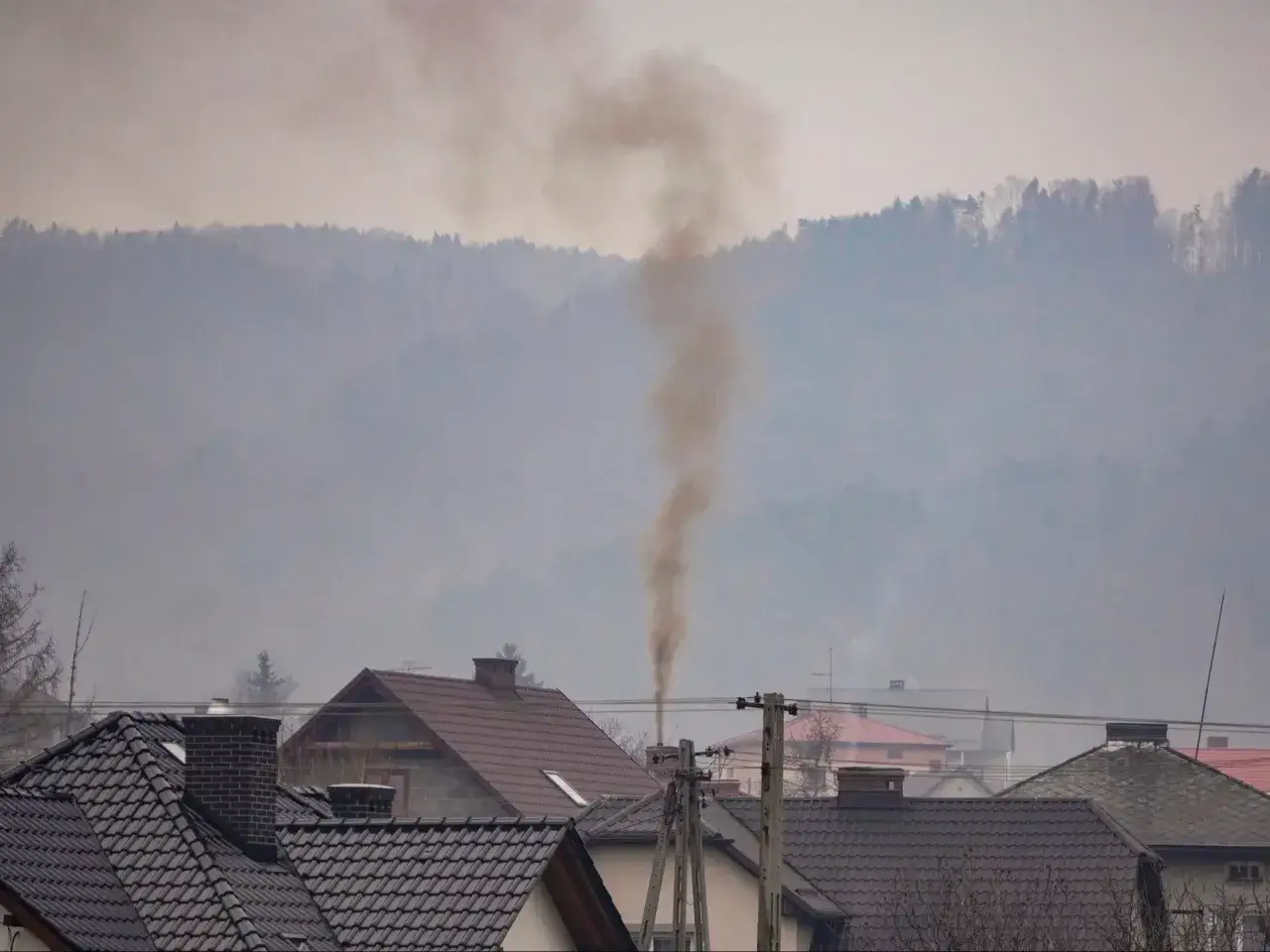 Dym z komina unosi się w mglistym powietrzu, wskazując na złą jakość powietrza w okolicy.