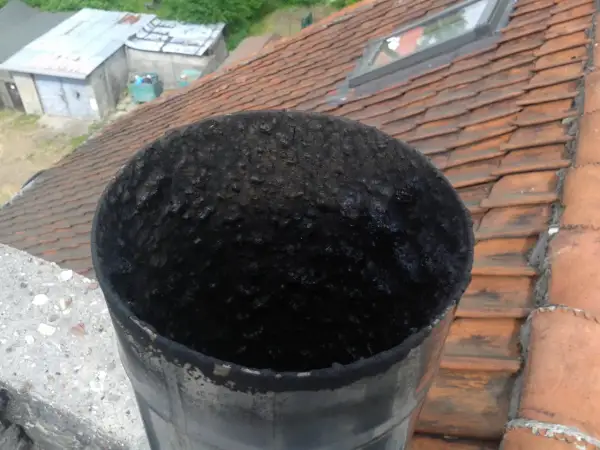 Zatkana sadzą rura kominowa. Zastanawiasz się, ile wytrzymuje wkład kominowy? Ten widok sugeruje, że czyszczenie jest konieczne.