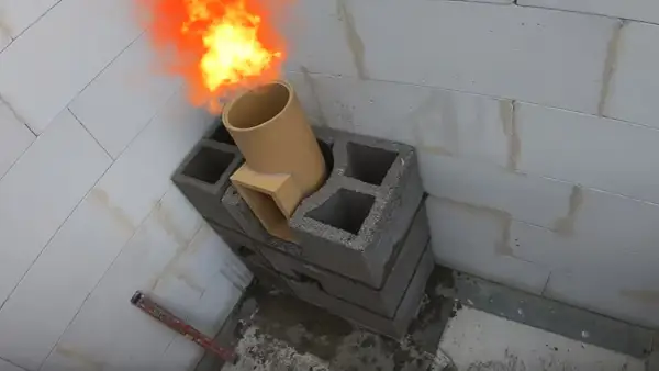Ogień wydobywa się z ceramicznej rury, która jest częścią mocowania komina systemowego do ściany z pustaków.
