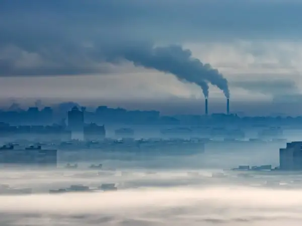 Mglisty poranek nad miastem, z kominów fabrycznych wydobywa się dym. O3 co to za zanieczyszczenie?