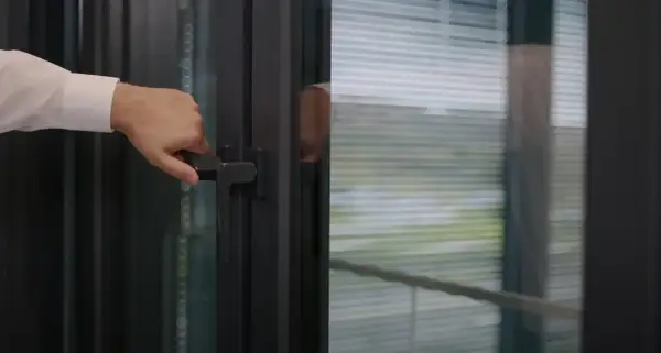 Dłoń chwyta klamkę okna, ustawiając je w pozycji mikrowentylacji.